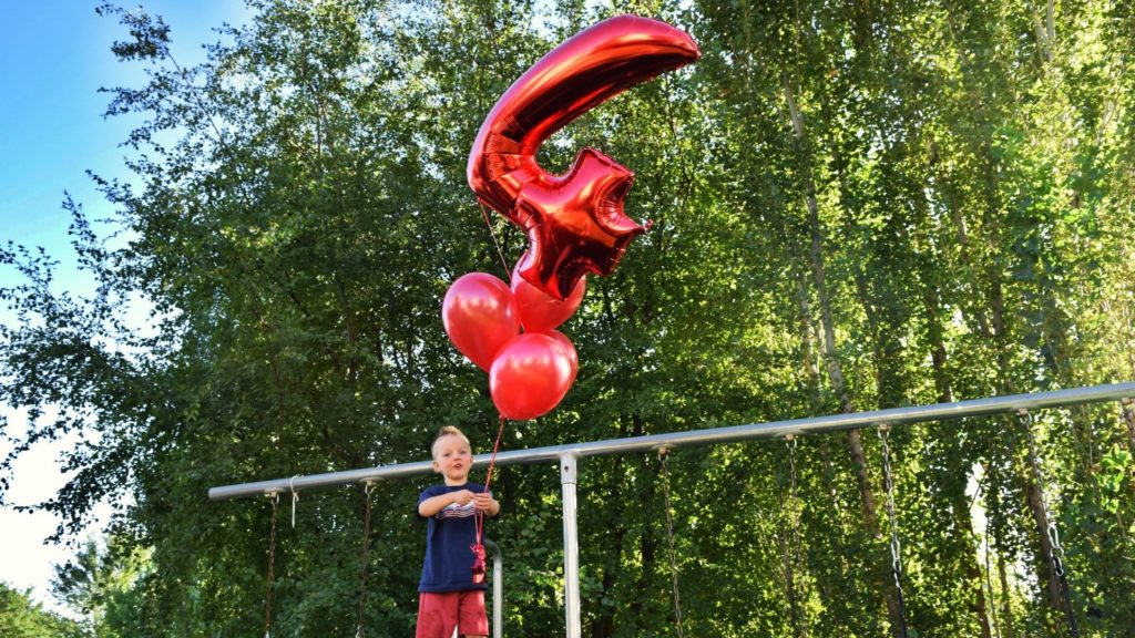 Charlie holding balloons while standing on a slide